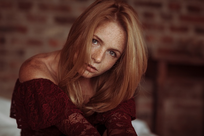 Woman with freckles wearing a red lace top