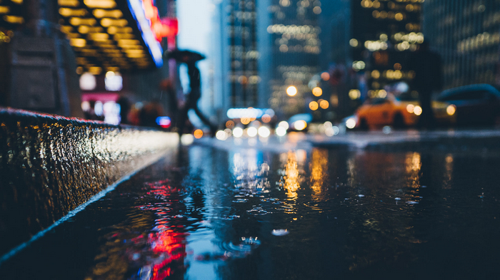 Rainy City Street with Blurred Lights and Cars