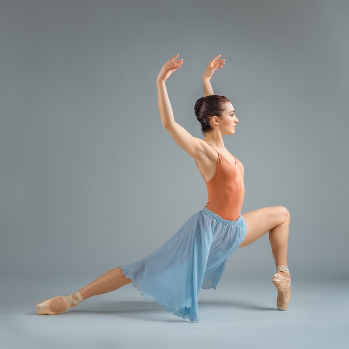 Ballerina in a leotard and skirt on a gray background