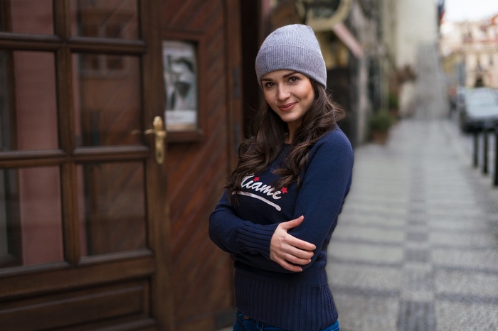 Woman wearing a hat and sweater on a street