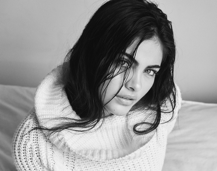 Monochrome portrait of a woman with black hair wearing a white sweater