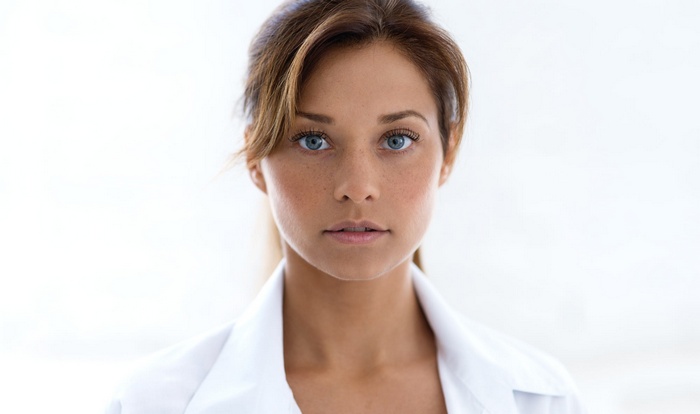 Woman with blue eyes and freckles wearing white clothing