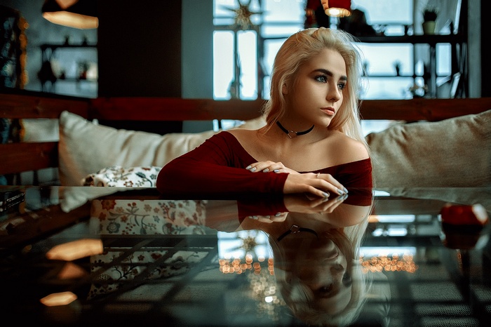 Woman with blonde hair wearing a maroon off-the-shoulder top