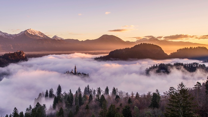 Church and castle above mist in Slovenia with mountains