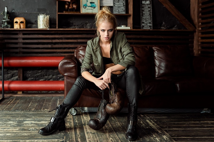 Woman with boxing gloves sitting on a leather couch