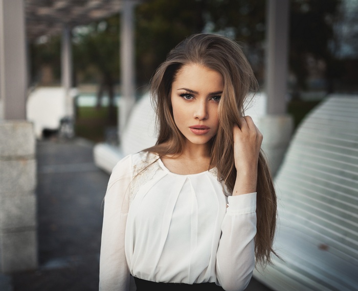 Woman with long brown hair touching her hair outdoors
