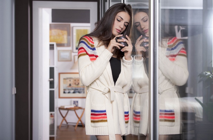 Woman in sweater holding mug indoors