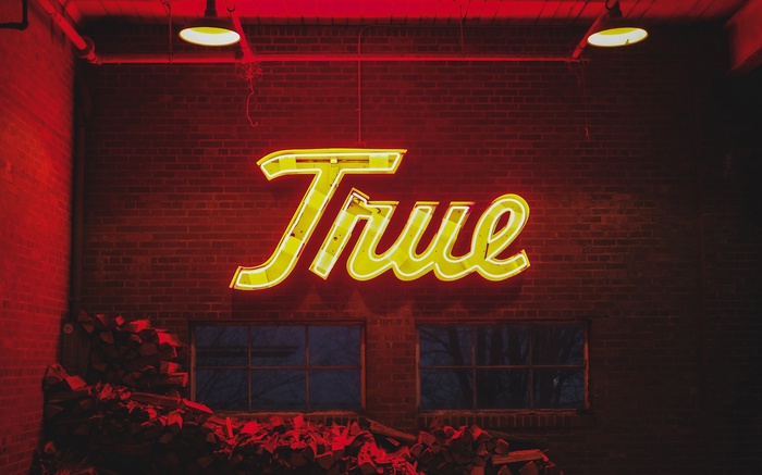 Yellow neon sign spelling "True" on a brick wall