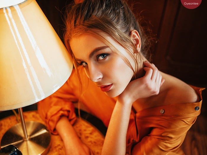 Woman in orange shirt near a lamp