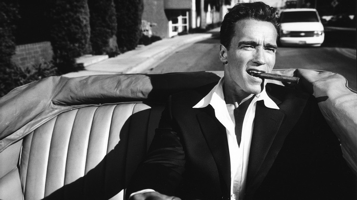 Arnold Schwarzenegger in a convertible with a cigar