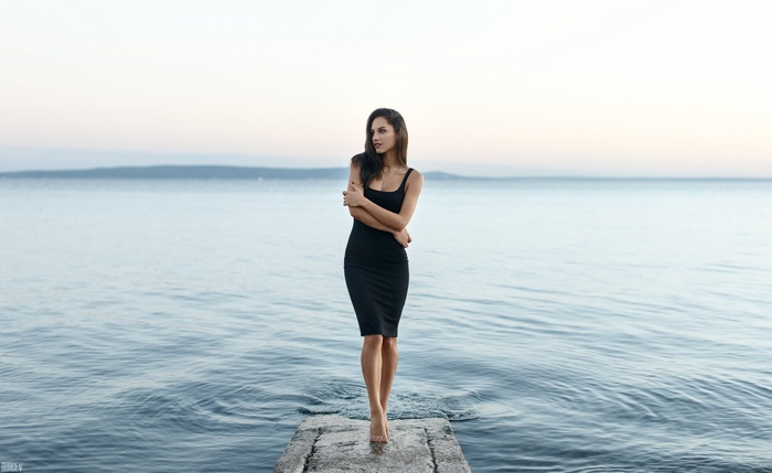 Woman in black dress on a pier by the sea