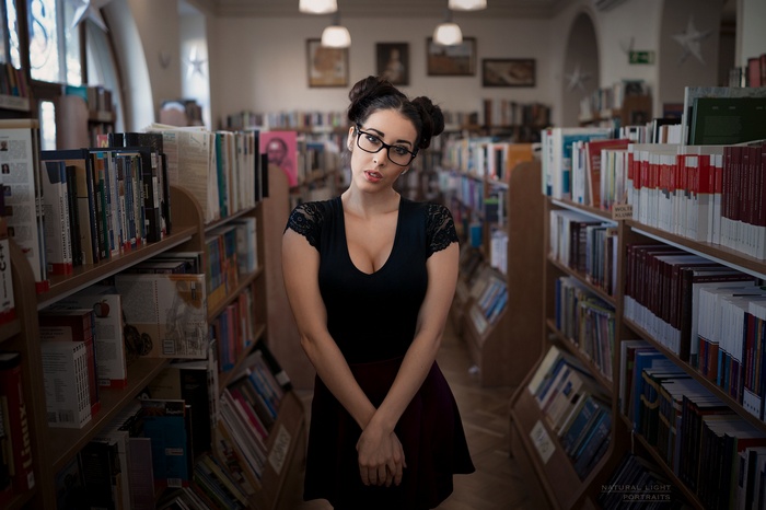 Woman with hair buns and glasses in a library
