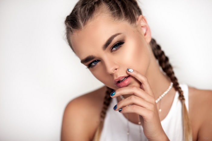 Woman with braids and blue eyes touching lips