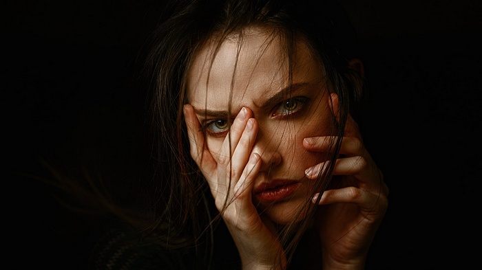 Portrait of a woman with hands covering her face