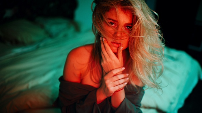 Woman with blonde hair sitting on a bed
