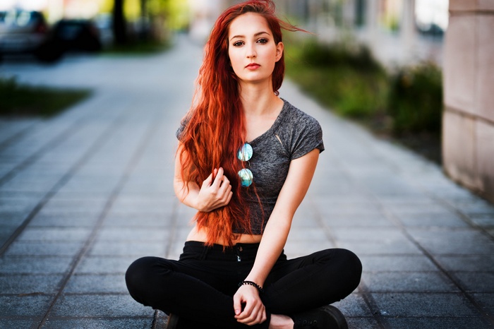 Woman with long red hair sitting outdoors