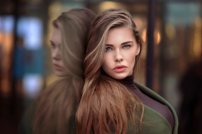Woman with blue eyes and blonde hair reflected in glass
