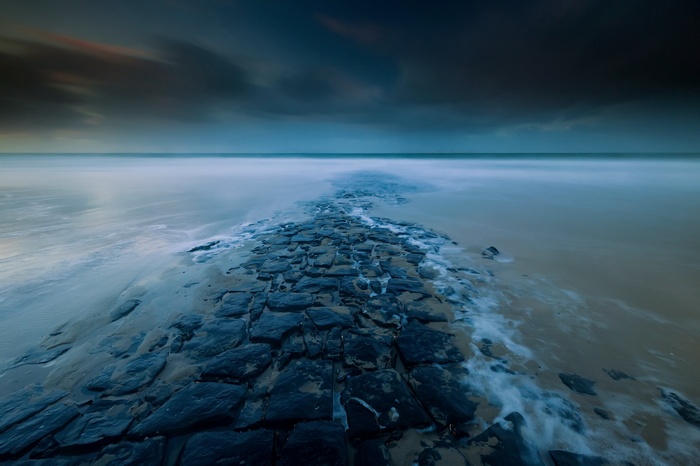 Stone path leading into the ocean at dusk