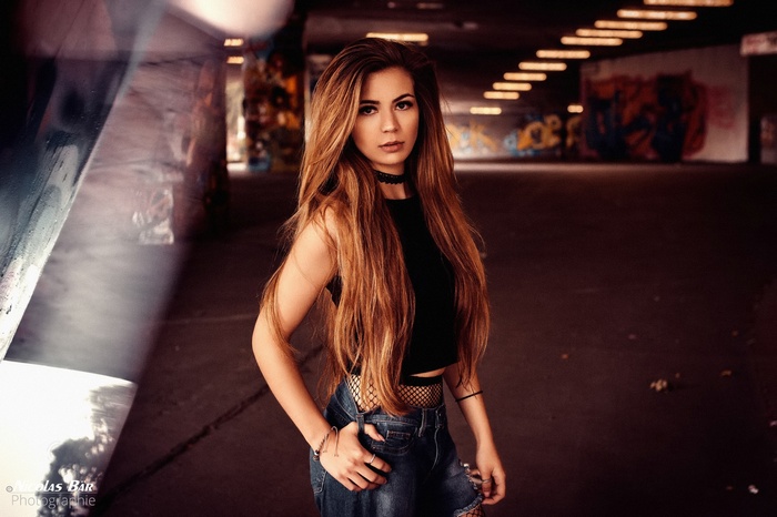 Woman with long brown hair wearing black top and ripped jeans