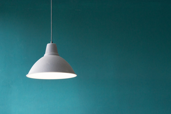 Minimalist gray pendant lamp against a teal wall