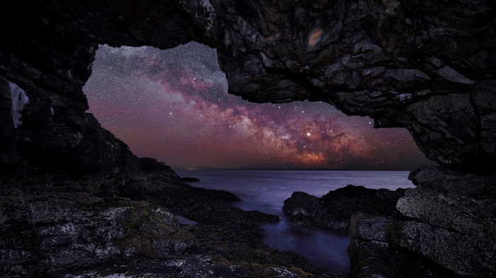 Milky Way seen through a cave opening over the sea