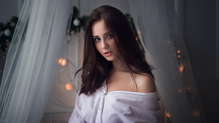 Woman with long brown hair wearing a white shirt