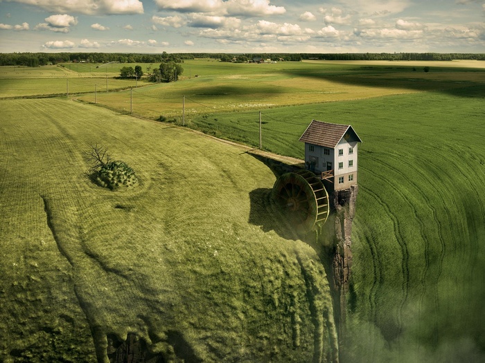 Surreal landscape with house on cliff edge and water wheel
