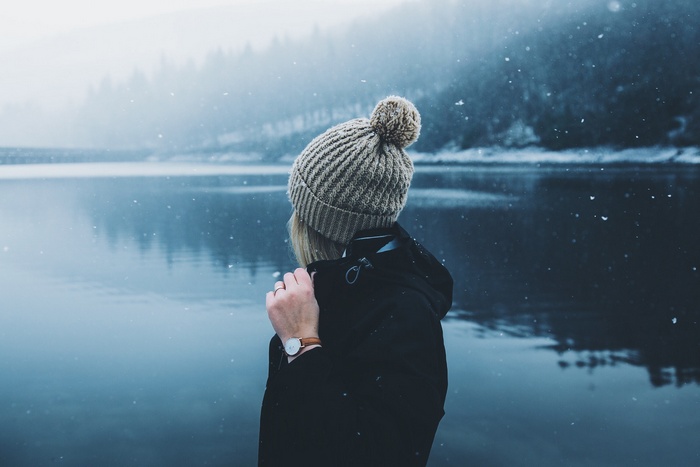 Woman in a beanie by a lake in the snow