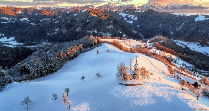 Snowy mountain landscape with a church at sunset