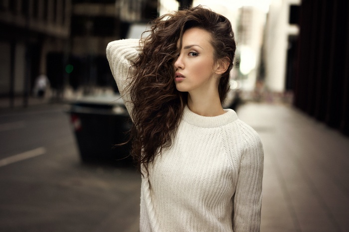 Portrait of a woman in a white sweater outdoors