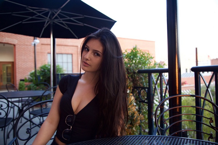 Woman with long dark hair sitting at an outdoor cafe