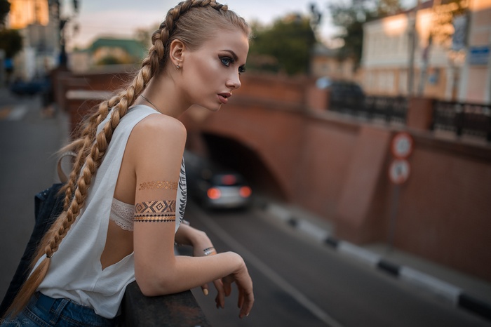 Woman with blonde braids and arm tattoos