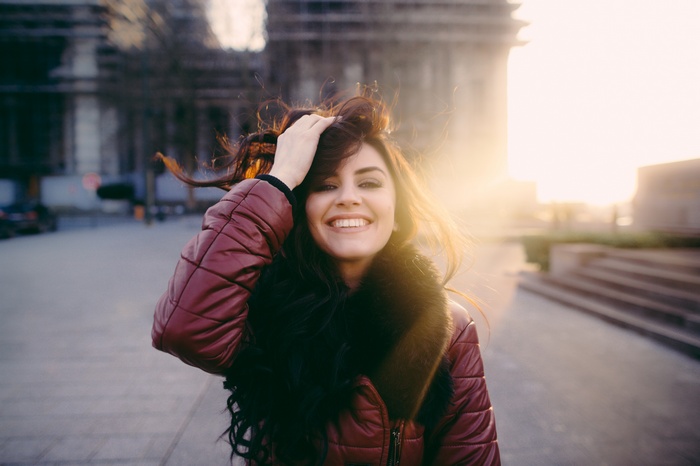 Woman with hand in hair smiling outdoors