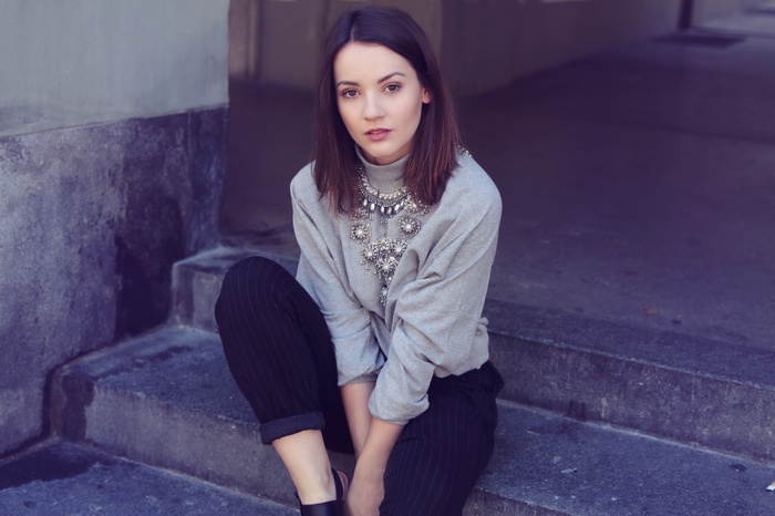 Woman wearing a grey shirt and necklace sitting on steps