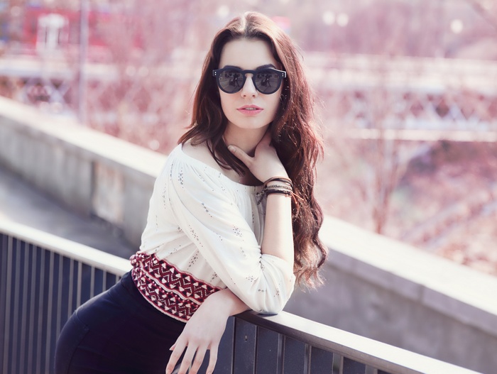 Woman with sunglasses and white shirt leaning on railing