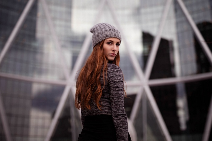 Woman in grey beanie and sweater looking over shoulder