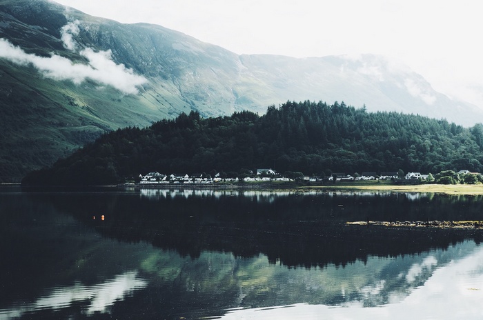 Village by a lake with mountains and mist