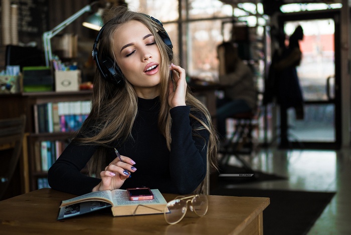 Woman with headphones listening to music in a library