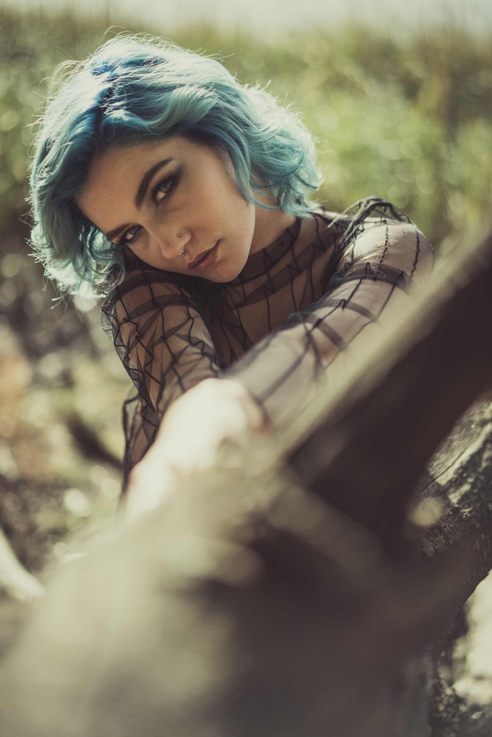 Woman with blue hair leaning on a log