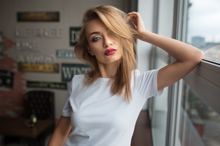 Woman with blonde hair and red lipstick by the window