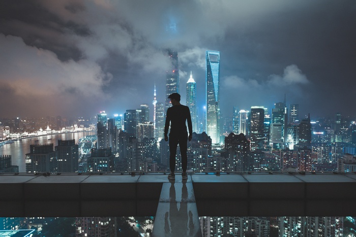 Man standing on skyscraper overlooking Shanghai at night
