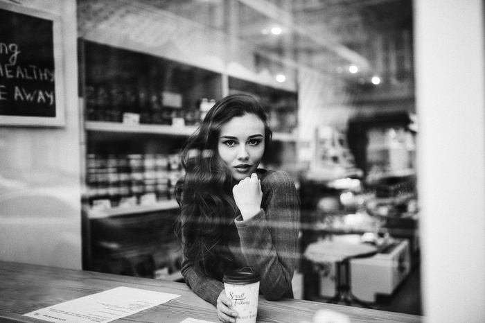 Woman with coffee cup looking through window