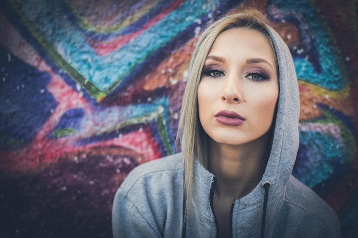 Woman with blonde hair and nose ring in front of graffiti
