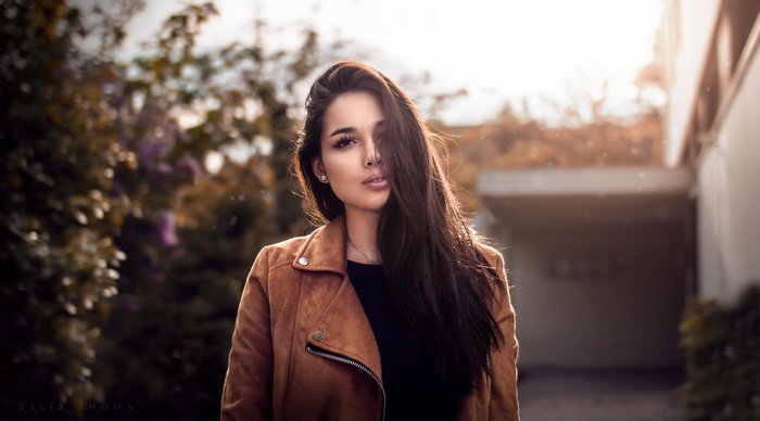 Woman with long dark hair wearing a brown jacket