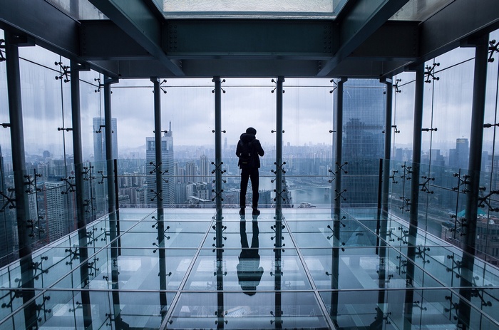 Person on glass floor overlooking cityscape