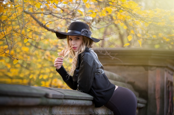 Woman in hat and leather jacket holding a leaf