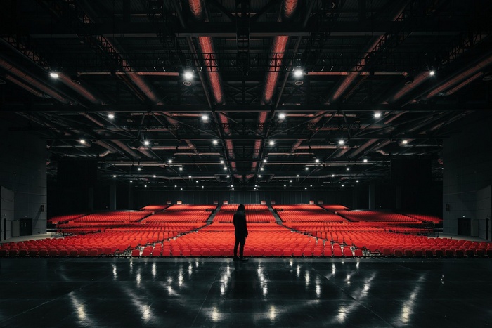 Person standing in an empty auditorium with red seats