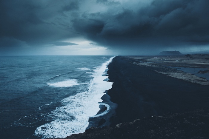 Black sand beach with stormy ocean and dark clouds
