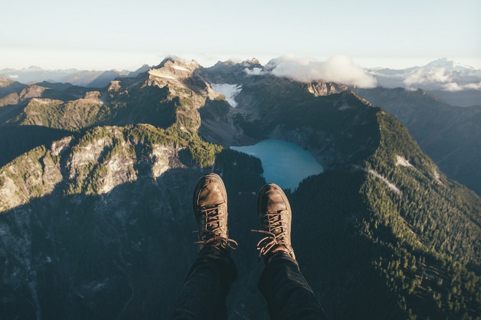 POV of hiker's boots overlooking mountains and lake