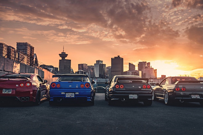 Nissan Skyline GT-R R34 and R35 cars in city at sunset
